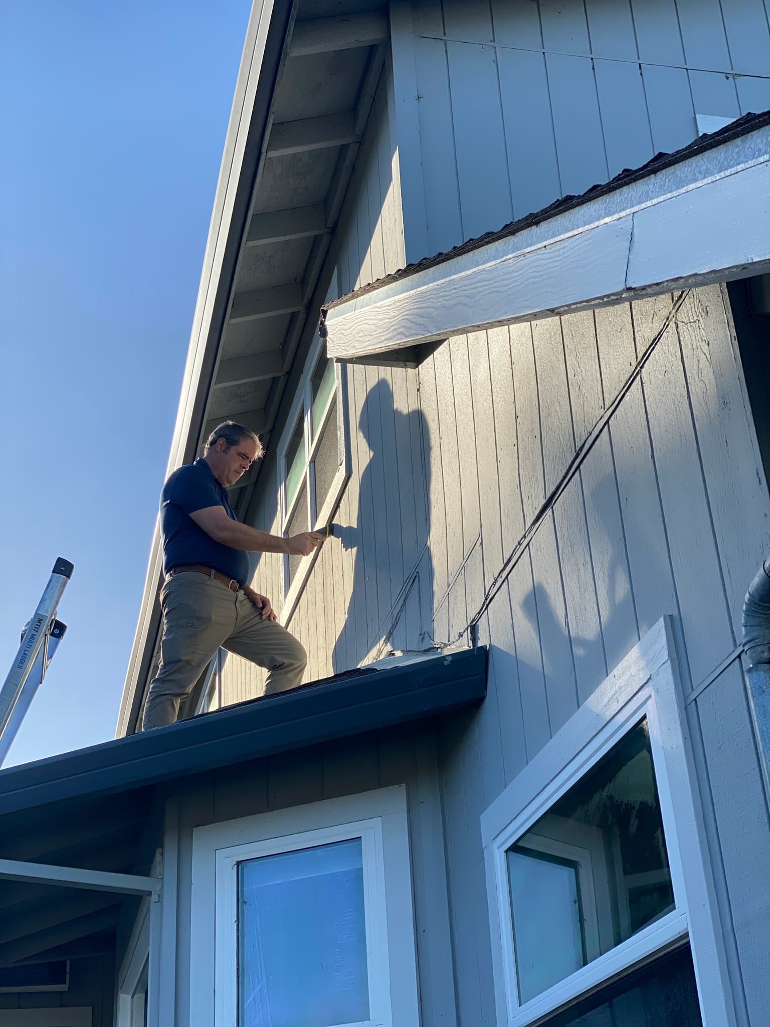 Juan de la Cruz inspecting the exterior of a Sonoma County home from the roofline